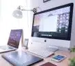 silver iMac near iPhone on brown wooden table